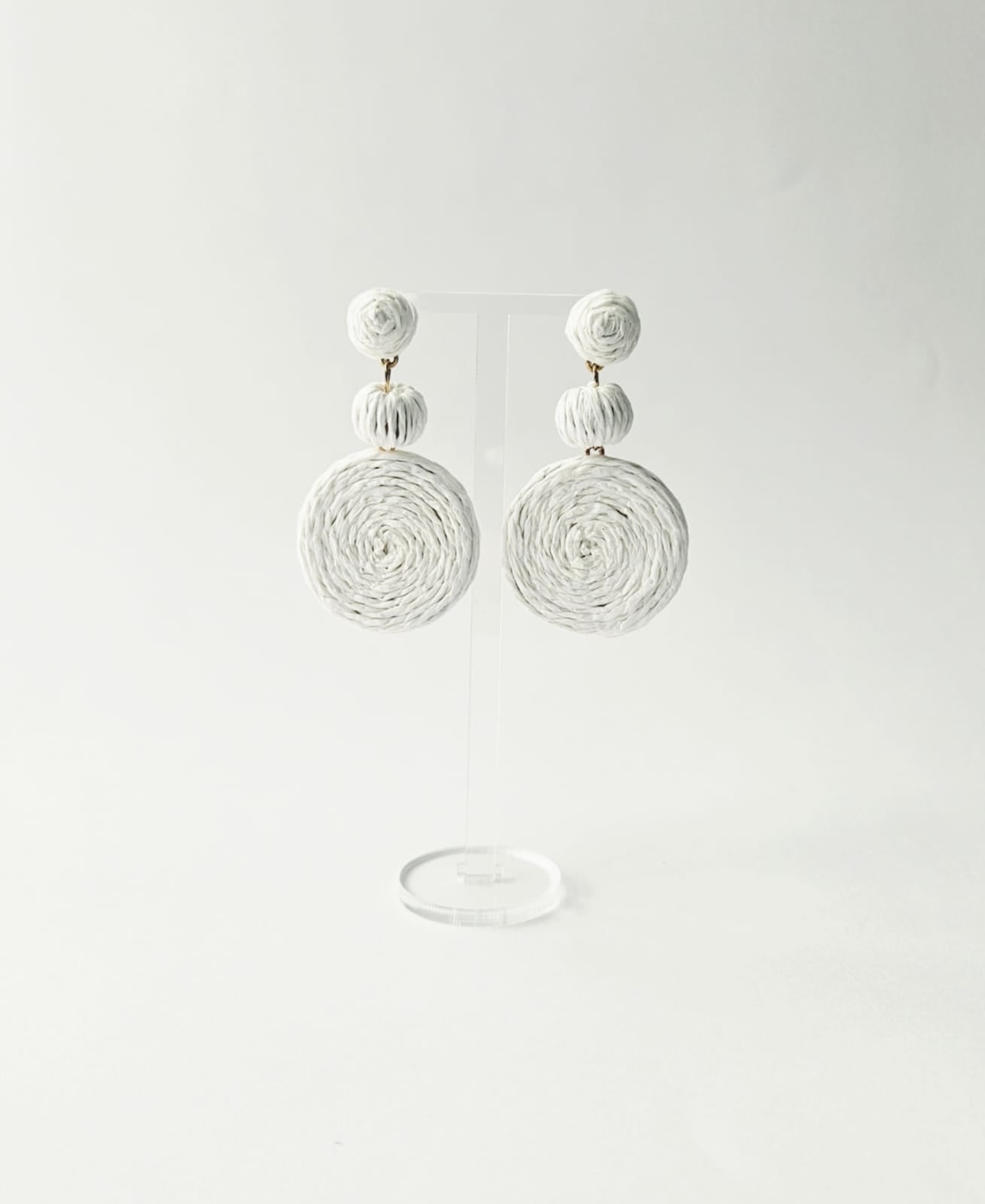 Pair of white bohemian style earrings on a light gray background