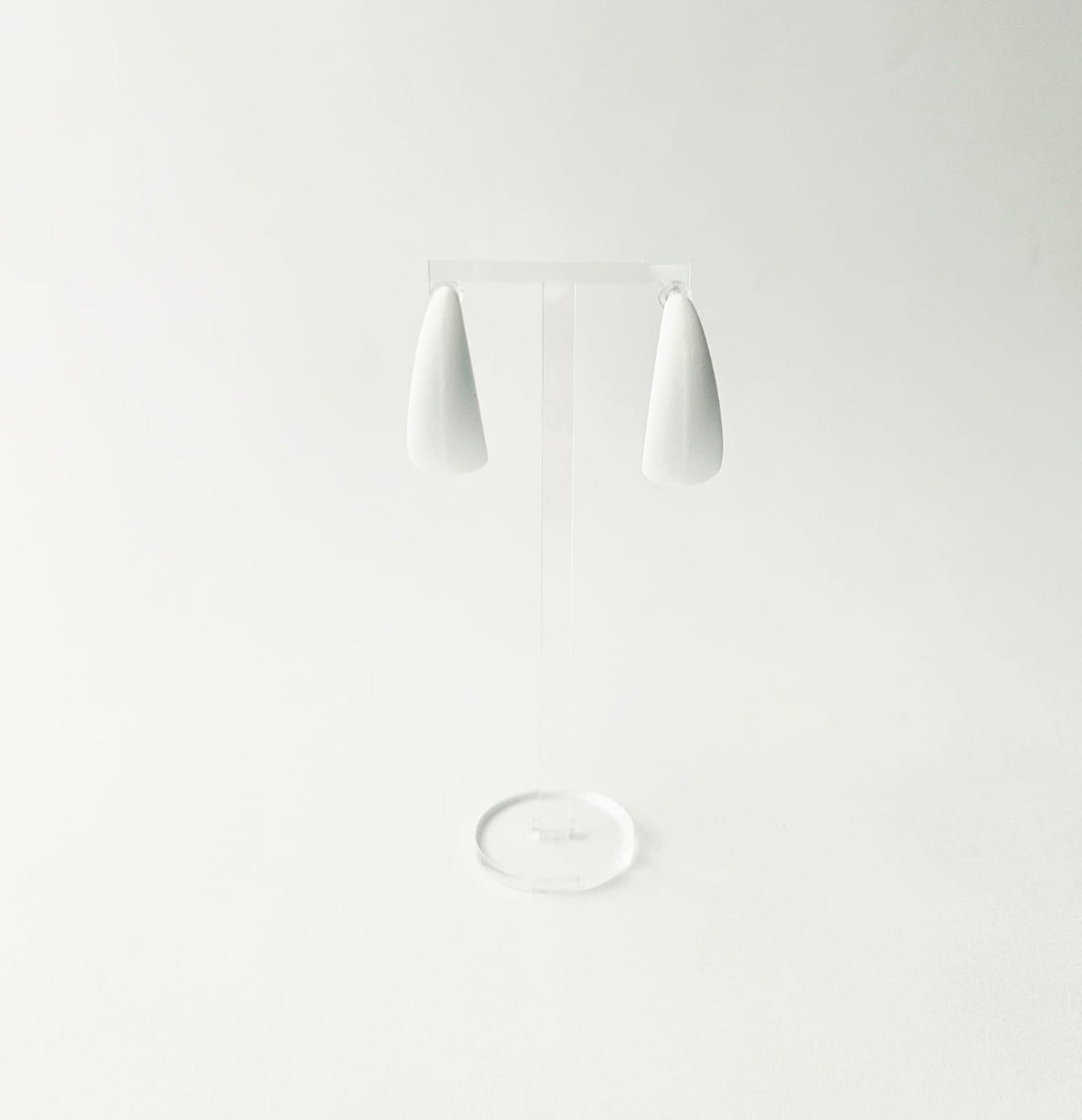 White C shaped hoop earrings on a light gray background