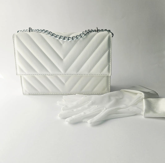 White handbag with a chain strap and white gloves on a light gray background