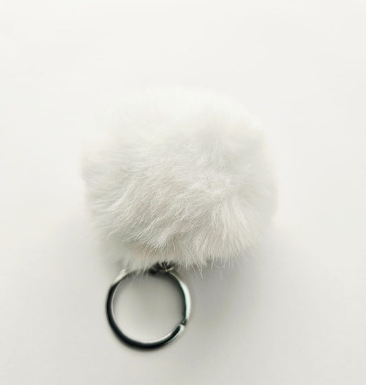 White fluffy pom-pom keychain on a light gray background