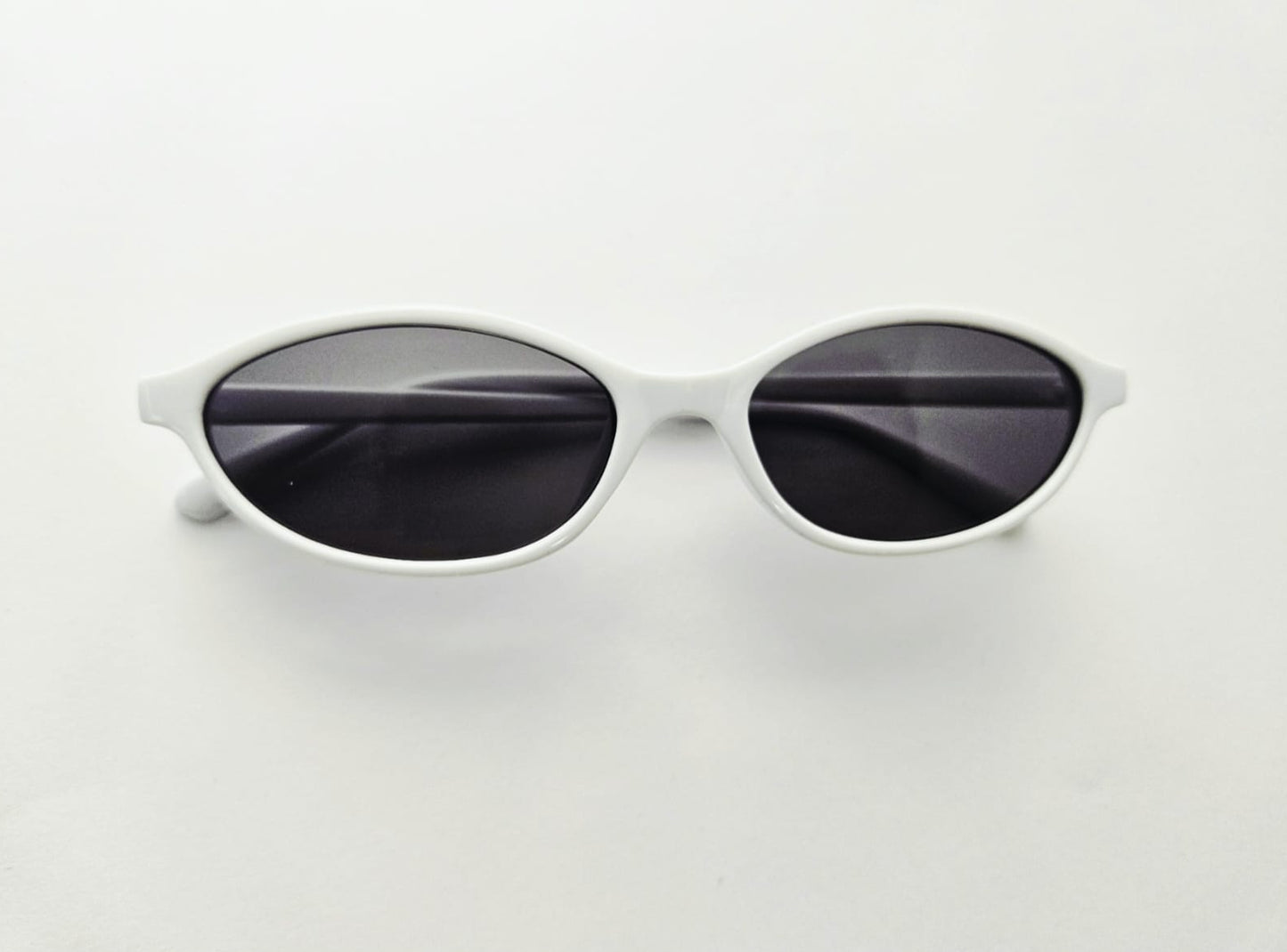 White framed sunglasses with dark lenses on a light gray background