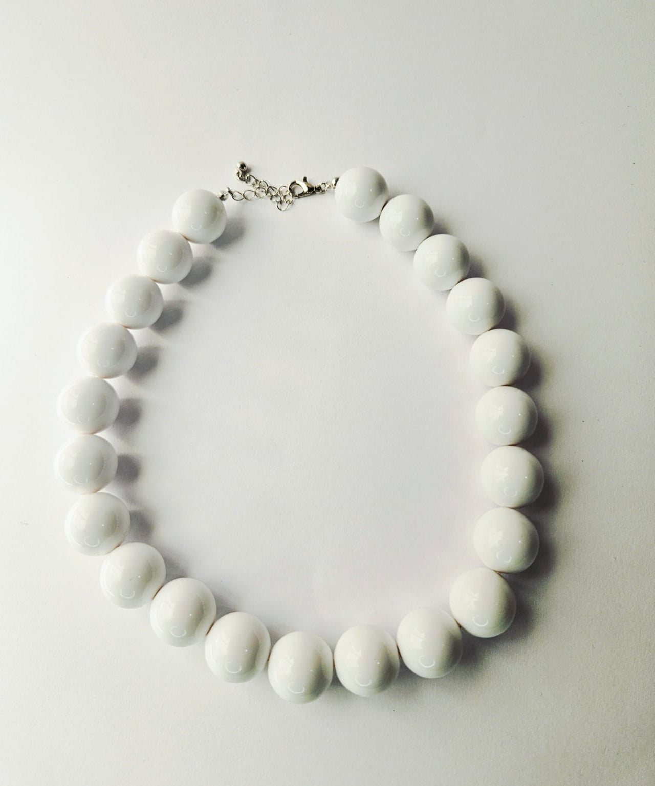 White beaded necklace on a light gray background