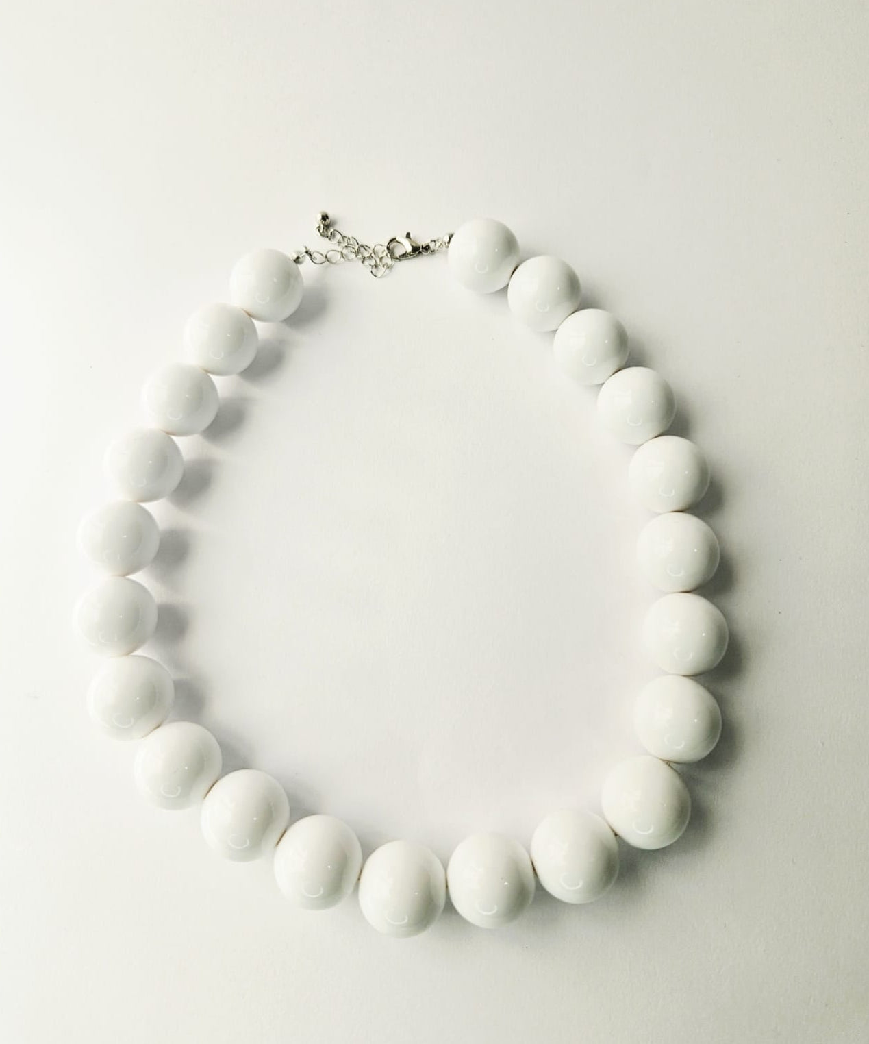 White beaded necklace on a light gray background